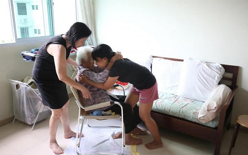 Helper sharing a warm caring hug with elderly client