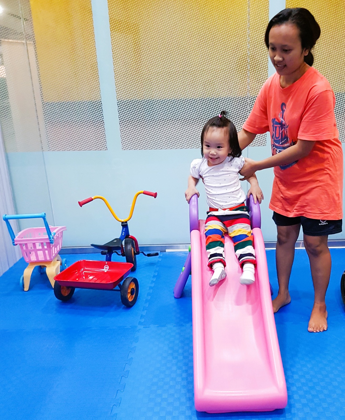 Helper playing with toddler on slide